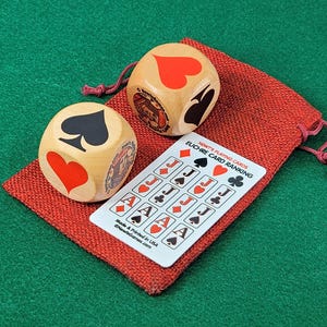 May include: Two wooden dice with red hearts and black spades on each side, along with a card ranking chart for the game of Euchre. The chart shows the ranking of cards in the game, with the Jacks being the highest ranking cards.