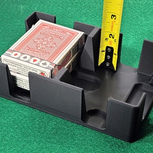 May include: A black plastic card holder with a deck of playing cards inside. The holder is 2 inches tall.