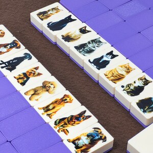 May include: Two rows of white dominoes with purple edges. Each domino features a different image of a cat or dog. The dominoes are arranged in a vertical line.