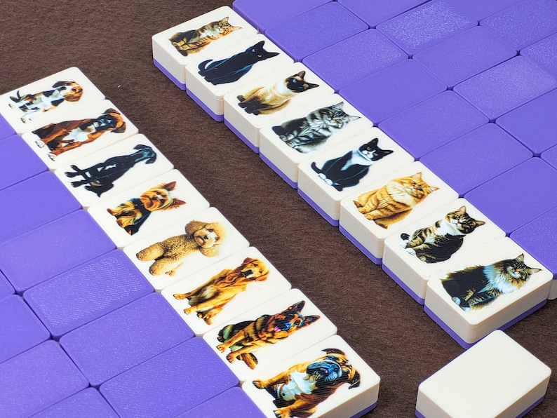 May include: Two rows of white dominoes with purple edges. Each domino features a different image of a cat or dog. The dominoes are arranged in a vertical line.