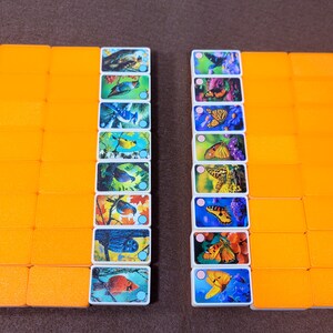 May include: A set of colorful dominoes with images of birds and butterflies. The dominoes are arranged in two rows, with the birds on the left and the butterflies on the right. The dominoes are all white with a blue border and a white dot in the center.