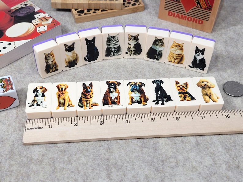 May include: A set of 12 white dominoes with images of cats and dogs. The dominoes are arranged in a semi-circle on a wooden surface. The dominoes are about 2 inches long and 1 inch wide. The images on the dominoes are clear and colorful.