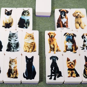 May include: A set of 12 dominoes featuring images of cats and dogs. Each domino has a white background with a colorful image of a cat or dog on one side.