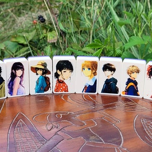 May include: Eight white rectangular tiles with blue edges, each featuring a different anime character illustration. The tiles are arranged in a row on a wooden surface.
