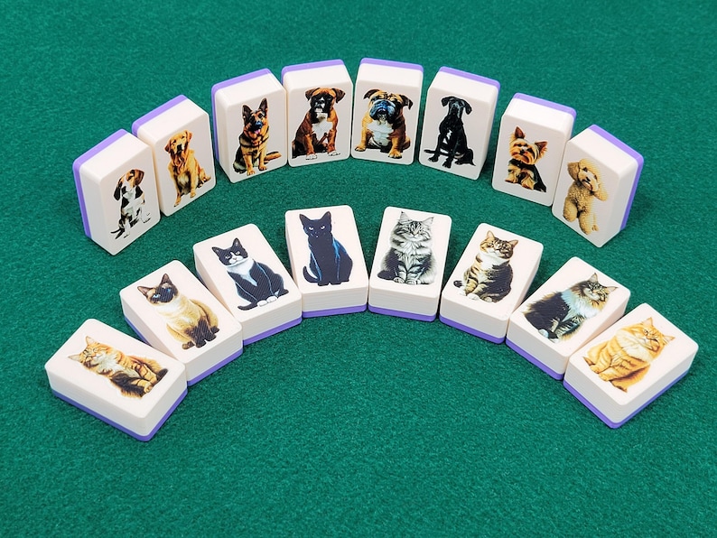 May include: A set of 16 dominoes featuring images of cats and dogs. The dominoes are white with purple edges and have a variety of breeds of cats and dogs on them.