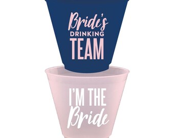 May include: Two plastic cups, one blue and one pink, with text. The blue cup says "Bride's Drinking Team" and the pink cup says "I'm the Bride".