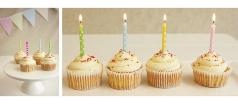 K&ouml;nnte beinhalten: Cupcakes mit Vanille-Frosting und bunten Streuseln, jeweils mit einer brennenden Kerze gekr&ouml;nt. Die Kerzen sind in verschiedenen Farben: gr&uuml;n, blau, gelb und rosa. Einige Cupcakes stehen auf einer wei&szlig;en Tortenplatte, andere auf einer wei&szlig;en Oberfl&auml;che.