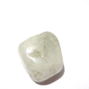 Könnte beinhalten: Ein einzelner Trommelstein mit einer glatten, polierten Oberfläche. Der Stein ist durchscheinend und cremeweiß, mit feinen inneren Einschlüssen und einer glänzenden Oberfläche, die das Licht auf seiner abgerundeten, unregelmäßigen Form reflektiert.