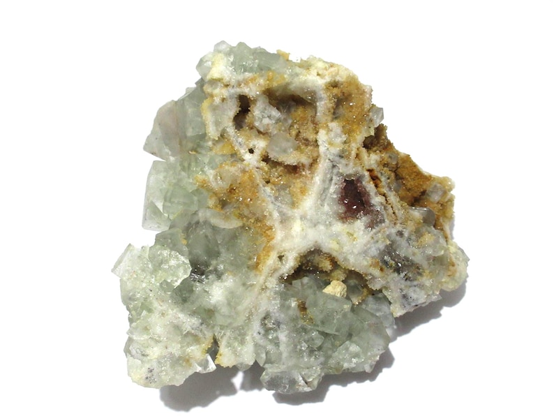 May include: A natural fluorite specimen with a mix of colors. The crystal structure is visible, with pale green and clear crystalline formations. The specimen also features areas of brown and white, creating a unique, textured appearance. The background is white.