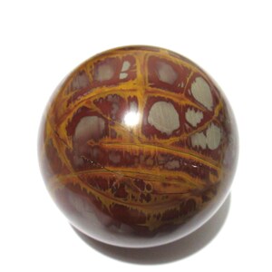 May include: A polished, spherical stone with a unique pattern. The orb features a mix of deep red, golden-yellow, and off-white colors. The surface has a glossy finish, and the design resembles a network of veins or patterns.