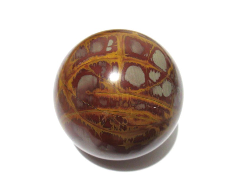 May include: A polished, spherical stone with a unique pattern. The orb features a mix of deep red, golden-yellow, and off-white colors. The surface has a glossy finish, and the design resembles a network of veins or patterns.