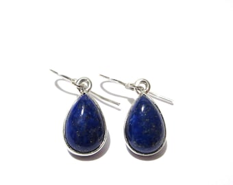 May include: A pair of teardrop-shaped earrings featuring deep blue lapis lazuli stones with subtle gold-colored flecks. Each stone is set in a smooth silver-toned metal bezel and hangs from a simple silver-toned metal hook ear wire.
