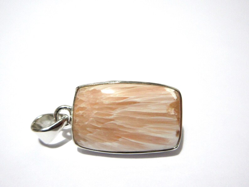 Pu&ograve; includere: Un ciondolo rettangolare con una cornice color argento. Il ciondolo presenta una pietra color pesca con striature bianche. La pietra &egrave; incastonata in una montatura in metallo color argento con un anello per una catena.