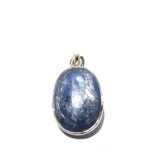 May include: An oval-shaped blue kyanite gemstone pendant set in a polished silver-toned metal bezel. The stone features a deep blue colour with visible natural striations and internal inclusions, topped with a small silver-toned metal bail.