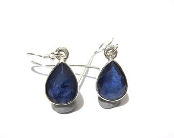 May include: A pair of silver drop earrings with pear-shaped, deep blue gemstones. The earrings have a simple, elegant design, with the gemstones set in a silver bezel and suspended from silver ear wires.