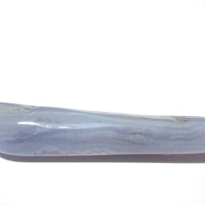 May include: A smooth, elongated blue lace agate gemstone. The stone has a pale blue color with subtle banding and a polished surface. The gemstone is approximately 5 inches long.