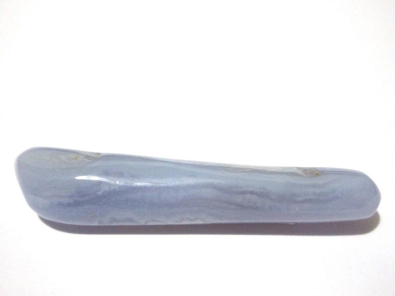 May include: A smooth, elongated blue lace agate gemstone. The stone has a pale blue color with subtle banding and a polished surface. The gemstone is approximately 5 inches long.