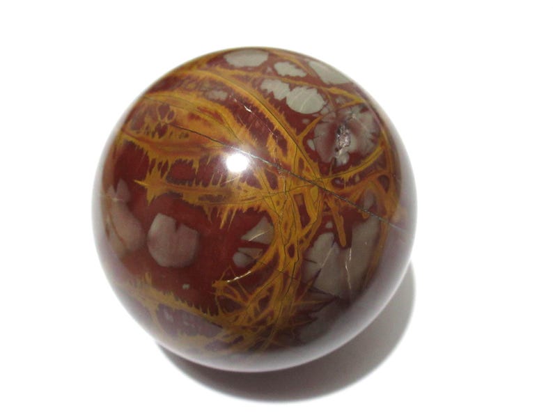 May include: A polished, spherical gemstone with a rich, reddish-brown base color. The stone features intricate patterns of golden-yellow veins and lighter, off-white inclusions, creating a unique and natural design. The sphere is smooth and reflective.