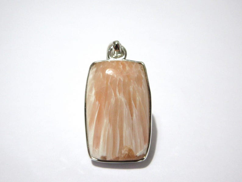 Pu&ograve; includere: Un ciondolo rettangolare con una cornice color argento. Il ciondolo presenta una pietra color pesca con motivi bianchi e piumati. L'anello &egrave; anch'esso color argento. Il ciondolo &egrave; probabilmente per una collana.