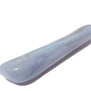 May include: A smooth, elongated blue lace agate gemstone. The polished stone has a rounded shape and a pale blue color with subtle white and tan marbling. The gemstone is approximately 4 inches long.
