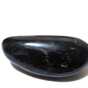 May include: A smooth, polished, dark blue and black stone with an elongated, rounded shape. The surface of the stone exhibits a glossy, reflective finish with subtle, irregular dark inclusions and faint hints of deep blue coloration throughout.