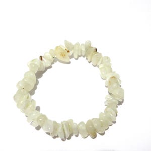 Peut inclure: Un bracelet composé de petites pierres précieuses de forme irrégulière, de couleur jaune-vert pâle. Les pierres sont enfilées ensemble, formant une forme circulaire. Le bracelet est posé sur un fond blanc.