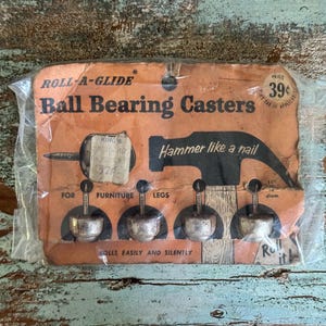 May include: A set of four silver-toned metal ball bearing casters in original orange cardboard packaging. The packaging features the text Roll-A-Glide, Ball Bearing Casters, Hammer like a nail, and For furniture legs, with a price of 39 cents.