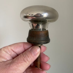 May include: A vintage glass door knob with a silver finish and a wooden base. The knob is attached to a metal rod.