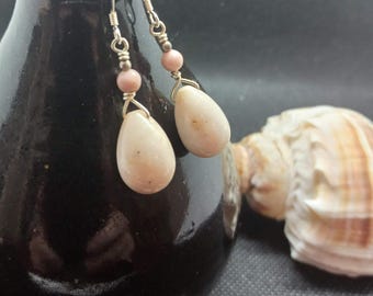 May include: A pair of silver dangle earrings with pink beads and white oval-shaped stones.