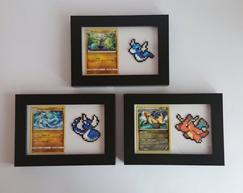 Puede incluir: Tres marcos de fotos negros con paspartús blancos, cada uno contiene una carta de Pokemon y una representación de pixel art del Pokemon. Los Pokemon son Dragonite, Dratini y Charizard.