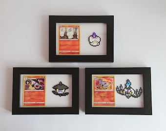 Puede incluir: Tres marcos negros con paspartús blancos, cada uno contiene una carta de Pokemon y una representación de pixel art del Pokemon. Los Pokemon son:  Linoone,  Lampent y  Chandelure.