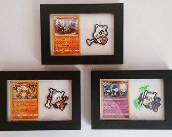 Puede incluir: Cuatro marcos negros con paspartús blancos, cada uno contiene una carta de Pokemon y una representación de pixel art del Pokemon. Los Pokemon son:  Cufant,  Marowak,  Marowak, y  Marowak.