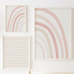 Set of three framed neutral rainbow and minimalist stripe prints in soft pastel tones, perfect for gender-neutral nursery wall decor.