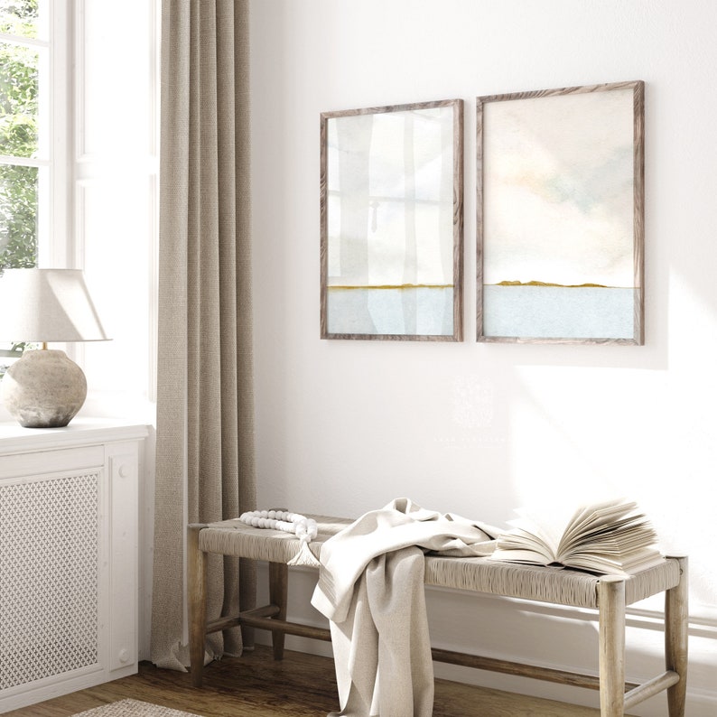 Two abstract seascape prints with soft watercolor textures, framed in vintage-style wood, perfect for coastal home decor.