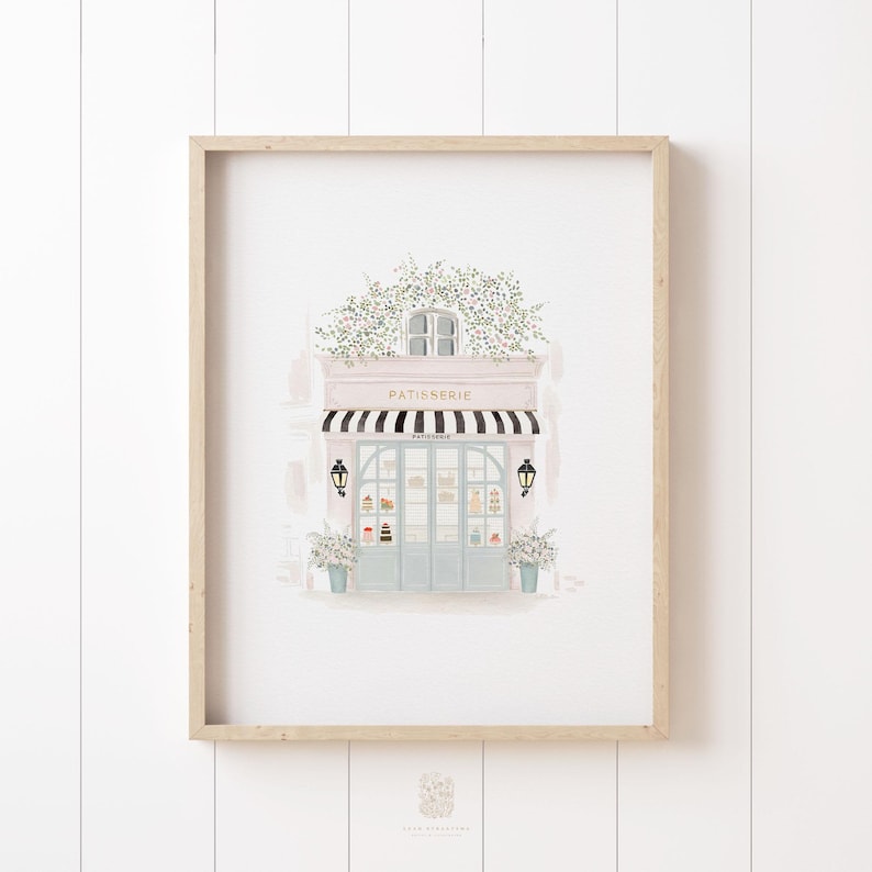 Soft watercolor illustration of a French patisserie storefront with a black-and-white striped awning, potted plants, and delicate floral details. A charming printable art piece for Paris lovers.