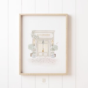 Elegant watercolor print of a boulangerie, framed and displayed on a neutral wall. A timeless piece of artwork for a bakery lover's home or a cozy kitchen setting.
