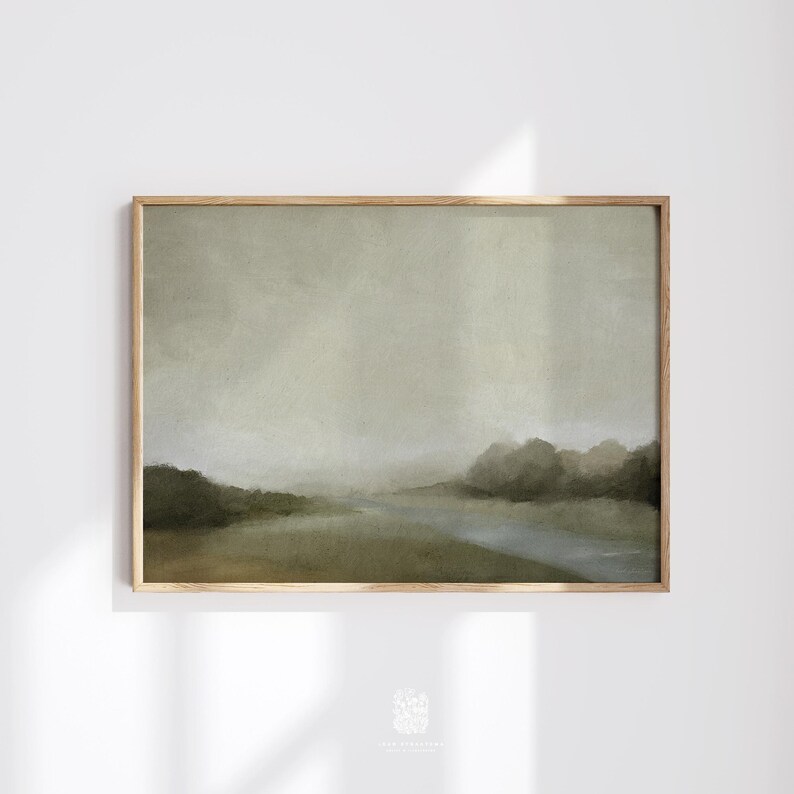 Framed neutral-toned landscape print featuring a soft misty sky, distant trees, and a river, shown against a white wall with gentle natural shadows.