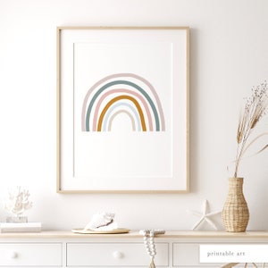 May include: A framed print of a rainbow with pastel pink, light blue, and green colours. The rainbow is in a minimalist style with rounded edges. The print is on a white background and is framed in a light wood frame.