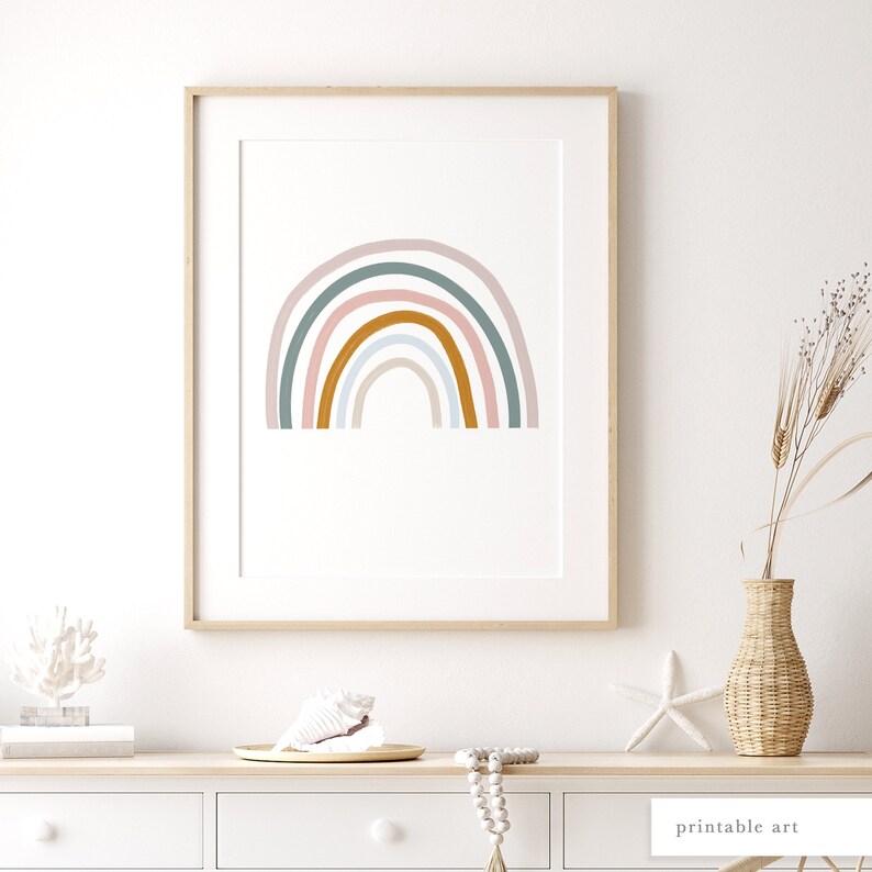 May include: A framed print of a rainbow with pastel pink, light blue, and green colours. The rainbow is in a minimalist style with rounded edges. The print is on a white background and is framed in a light wood frame.