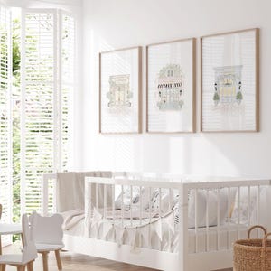 Cozy nursery with framed Paris-inspired watercolor storefront prints, adding a whimsical European touch to the decor. Ideal for a child's room or feminine wall art.
