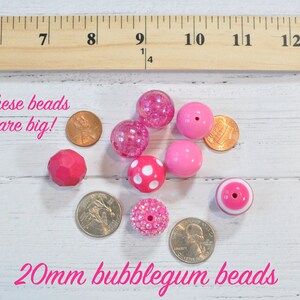 May include: A collection of pink bubblegum beads, approximately 20mm in size, with various textures and designs, including polka dots and glitter. The text "These beads are big!" and "20mm bubblegum beads" is visible.