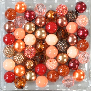 May include: A collection of colourful beads in various shapes and sizes, including round, square, and star-shaped beads. The beads are made of different materials, such as glass, plastic, and metal. The beads are arranged in a random pattern on a white surface with polka dots.