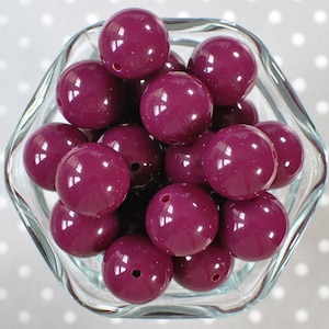 May include: A bowl filled with large, round, purple beads. The beads are shiny and have a smooth, glossy finish.