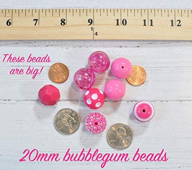 May include: A collection of 20mm bubblegum pink beads in various styles, including solid, speckled, and polka dot. The beads are shown next to UK currency for size comparison. "These beads are big!" is written in white text on a black background.