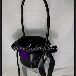 May include: Black satin flower girl basket with a purple satin ribbon and a skull charm. The basket has a black satin handle.