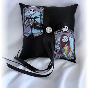 May include: Black pillow with a satin ribbon and a rhinestone brooch. The pillow features images of Jack Skellington and Sally from the Nightmare Before Christmas.