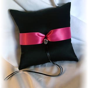 May include: Black ring pillow with a hot pink satin ribbon and a silver skull accent.