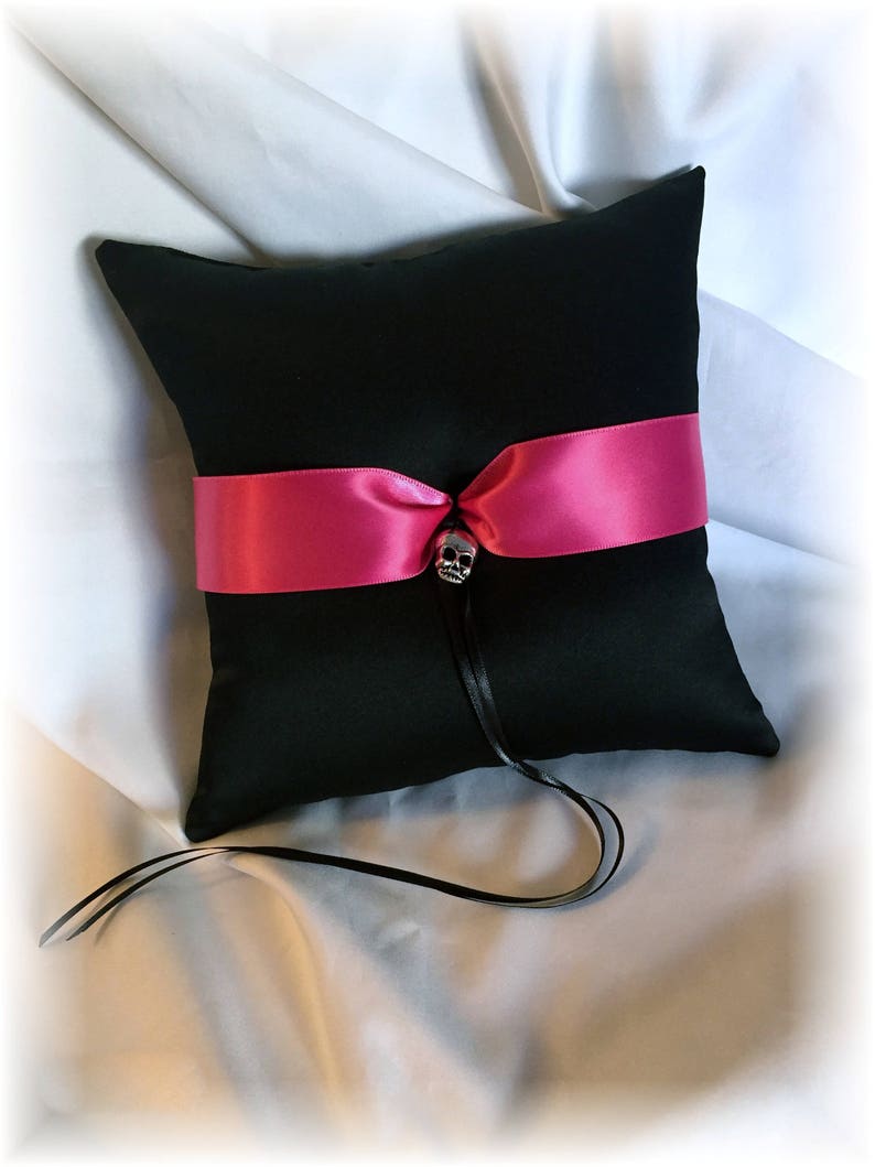 May include: Black ring pillow with a hot pink satin ribbon and a silver skull accent.