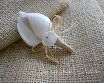 May include: A white seashell with a brown straw bow and a white sand dollar, on a burlap background.