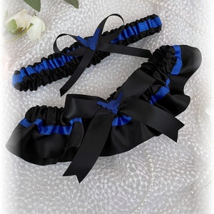 May include: A black and royal blue garter with a satin bow and a blue butterfly charm. The garter is made of satin and lace.
